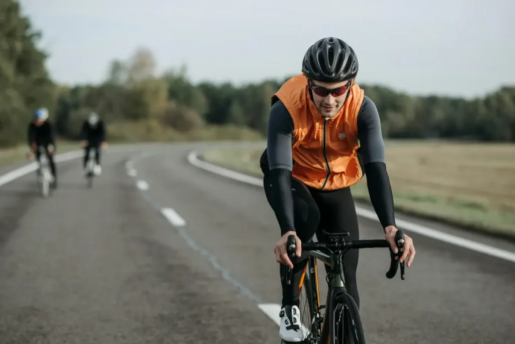 Hombre montando bicicleta en una carretera, disfrutando del ciclismo como ejercicio efectivo para perder peso.