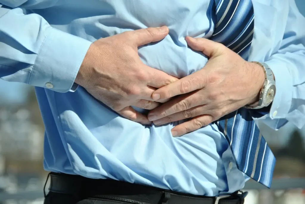 Hombre con dolor de estómago debido a los efectos secundarios de pastillas para adelgazar."