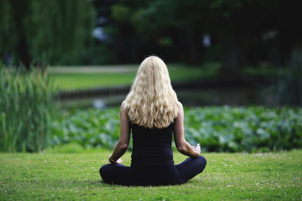 Mujer meditando en un entorno natural con expresión de tranquilidad