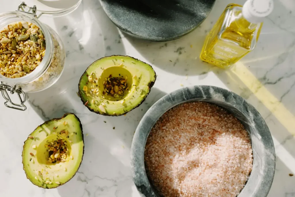 Fuentes de grasas saludables como aguacates, nueces y aceite de oliva para mejorar la hidratación de la piel.