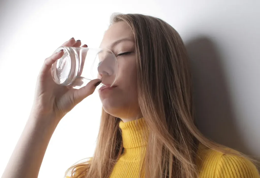  Persona bebiendo agua para mantenerse hidratada durante la diarrea.
