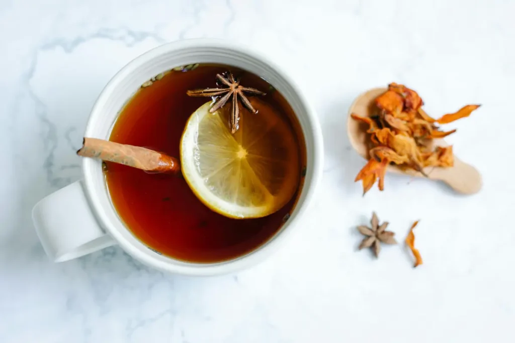 Infusión de canela en vaso de cristal con miel y manzanas, ideal para regular el azúcar en la sangre y reducir el almacenamiento de grasa.