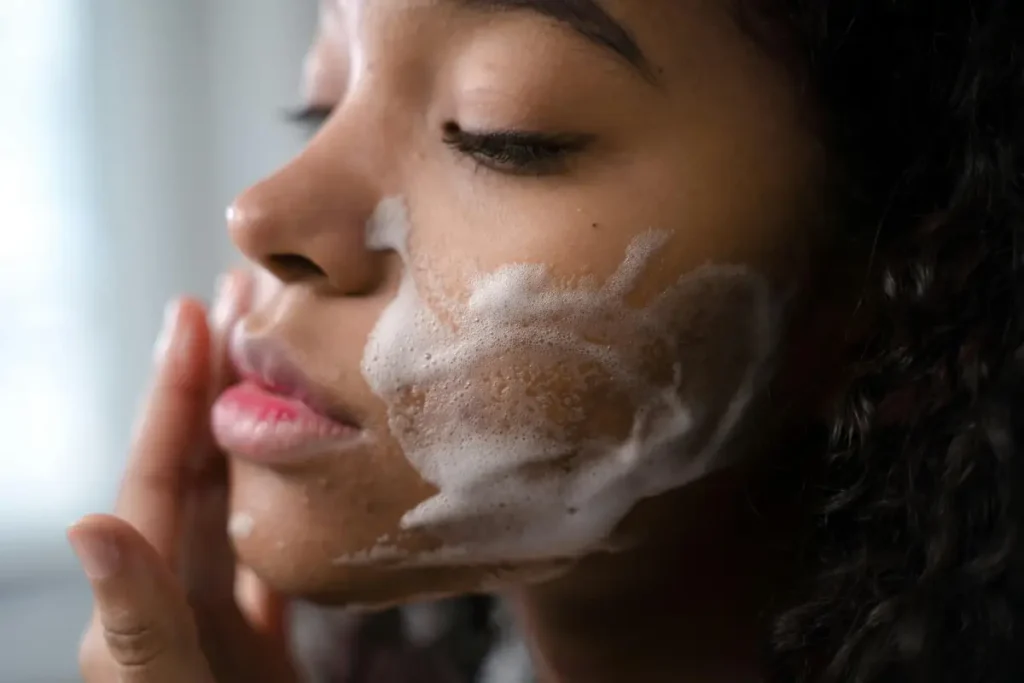 Persona realizando una limpieza facial con espuma para eliminar impurezas y prevenir el acné.