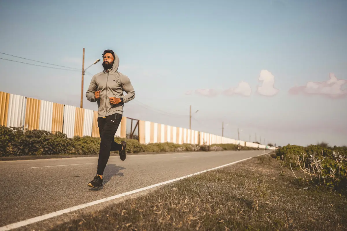 Persona corriendo al aire libre con un fondo soleado, representando una rutina de ejercicios para perder peso de manera efectiva y saludable.
