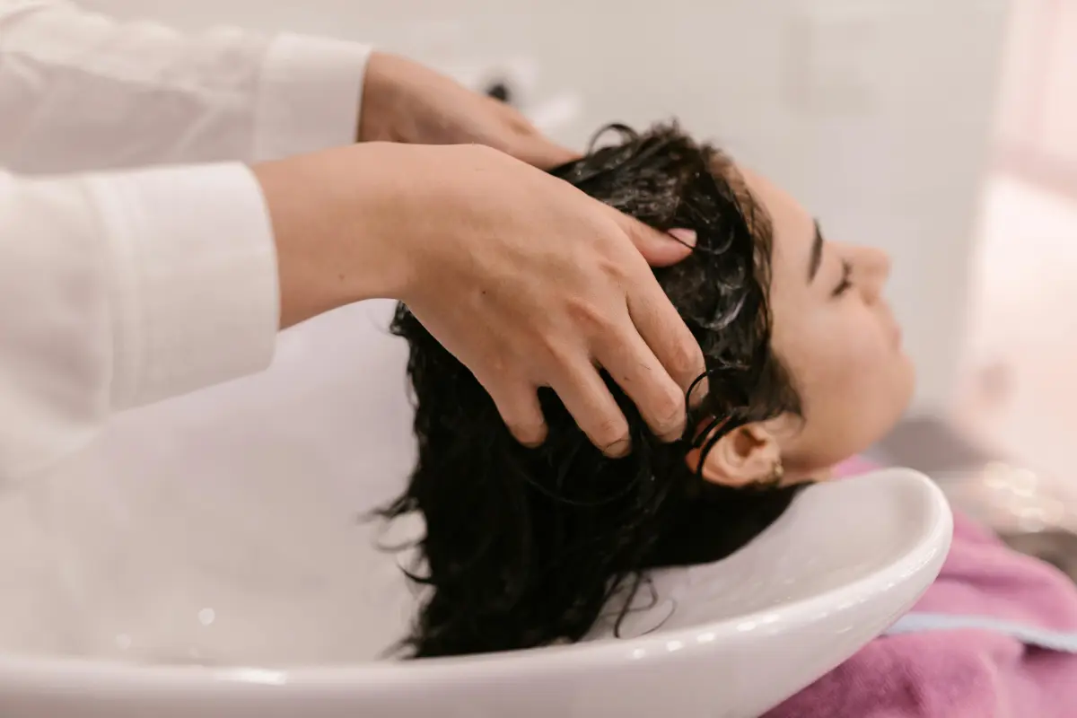 Mujer masajeando su cuero cabelludo con un tratamiento natural para eliminar la caspa.
