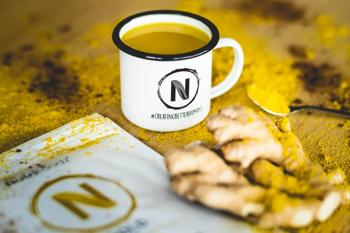 Infusión natural en taza con jengibre y miel sobre una mesa.