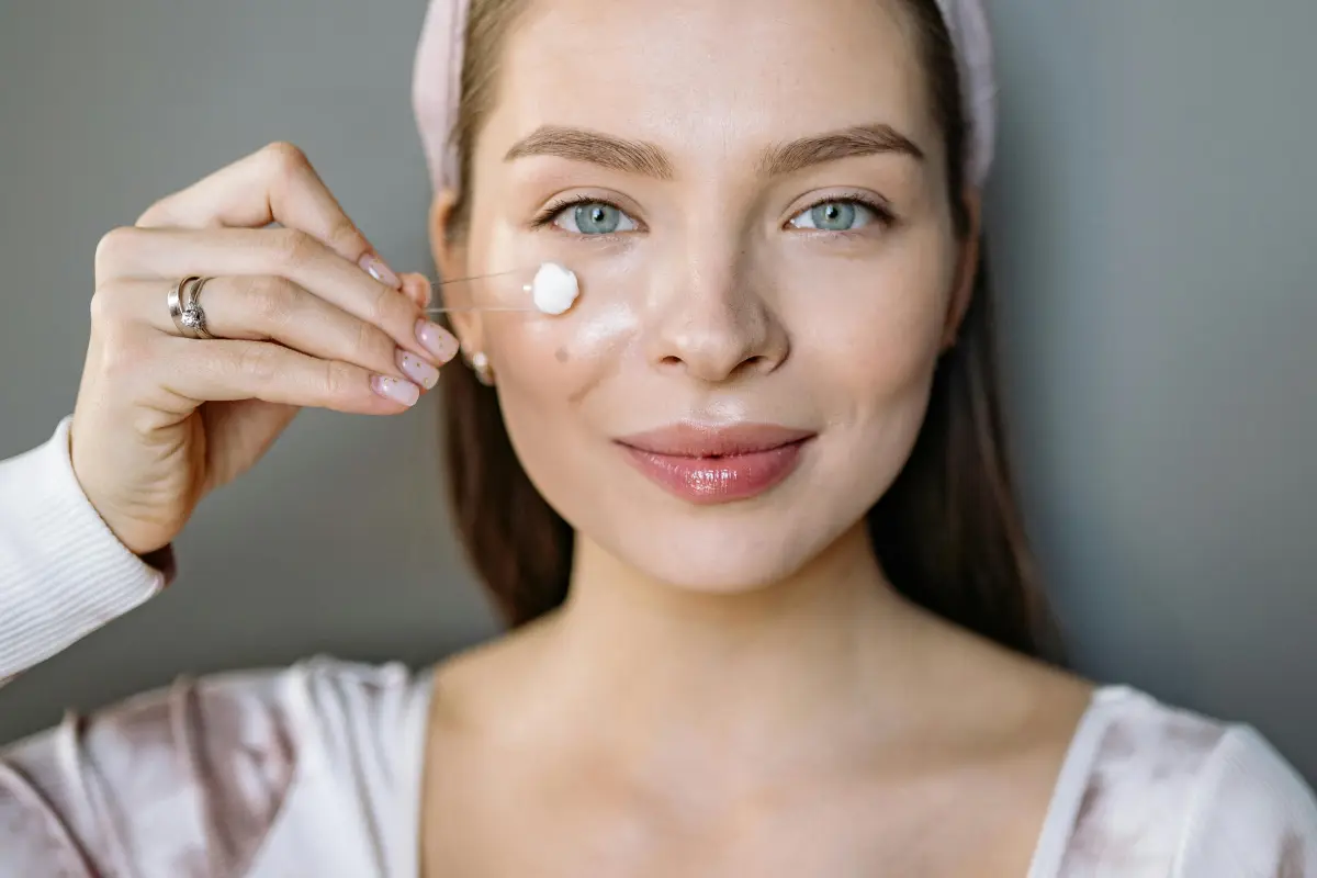Mujer con piel radiante aplicando crema facial, representando los mejores secretos de belleza.